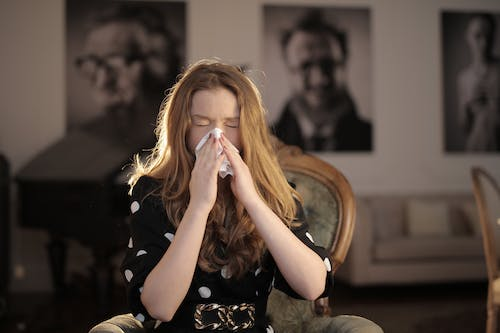 a woman sneezing on a tissue