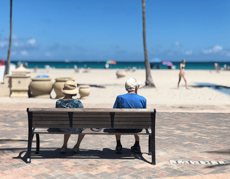 Two elderly people sit side-by-side on a park bench