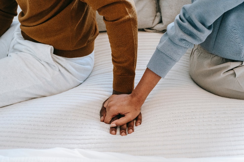 Couple holding hands on bed 