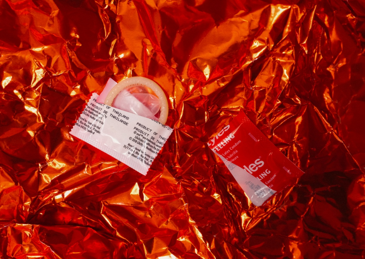 An open condom on a red sheet