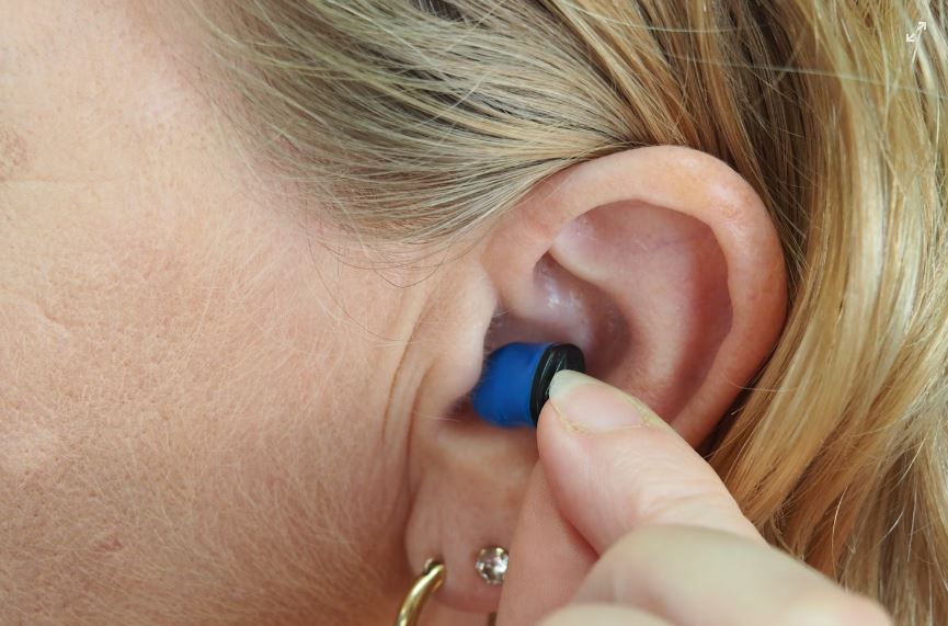 A person inserting an ear device into their ear