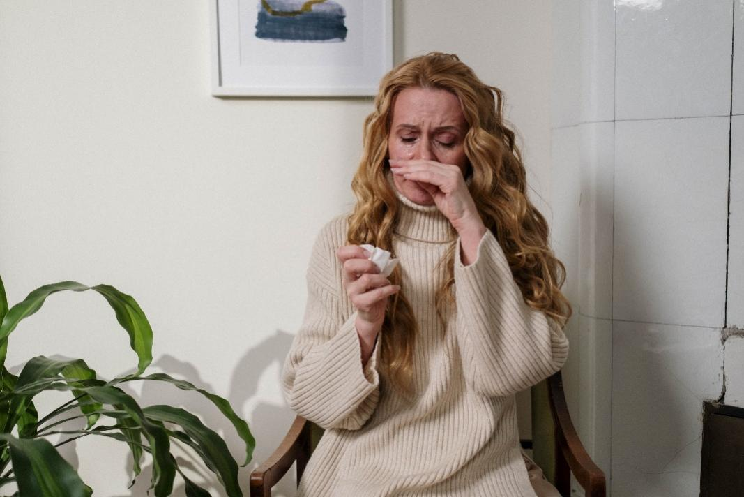 A woman wiping her nose after sneezing