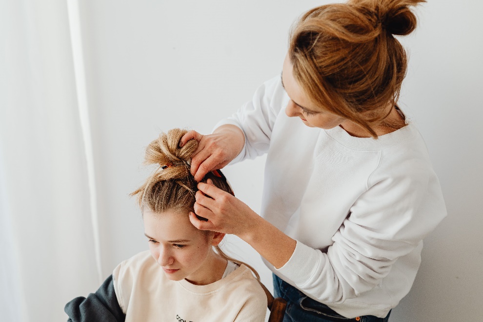 woman creating hairstyle on a girl