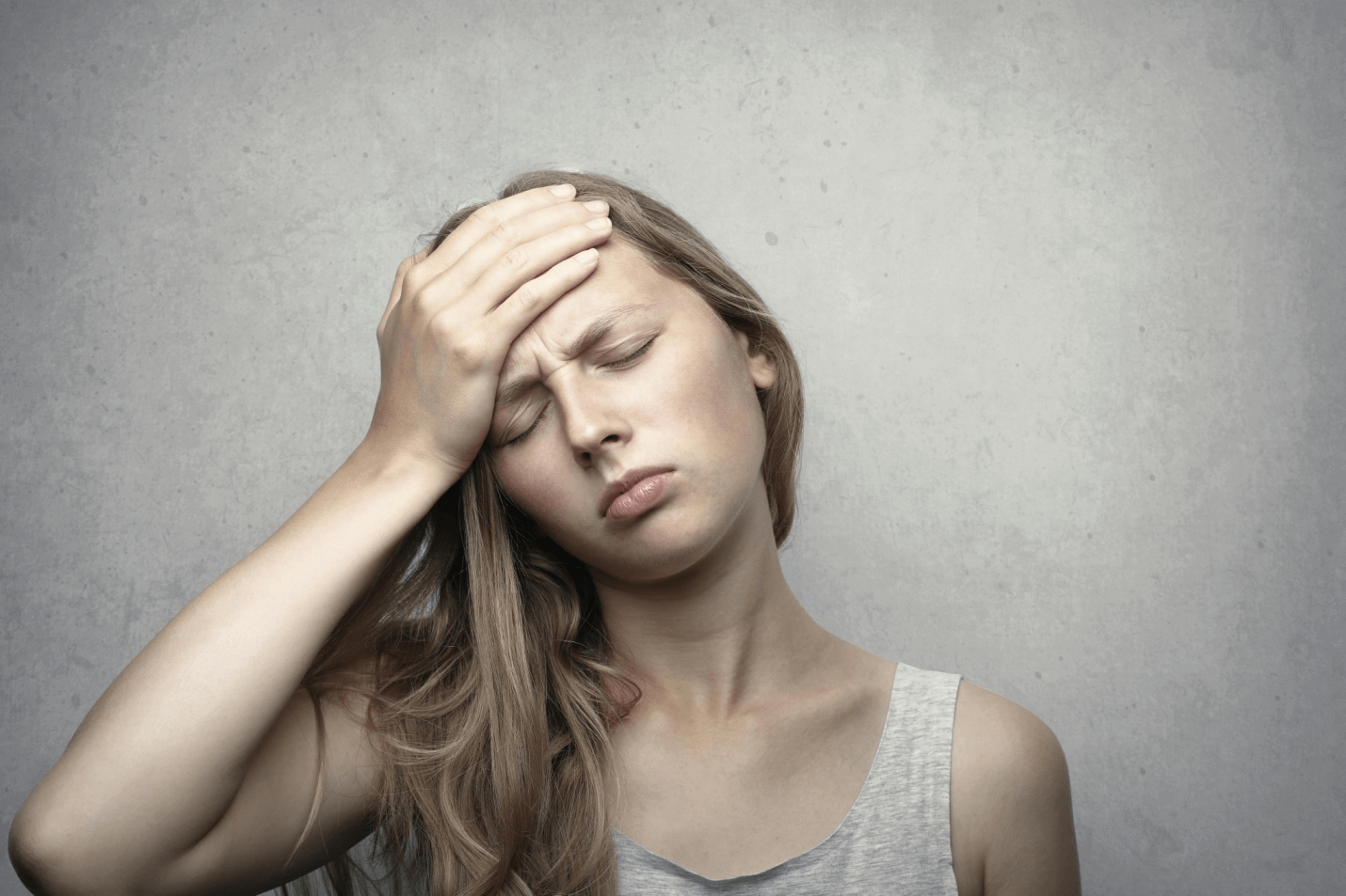 A woman experiencing discomfort from headaches and fatigue