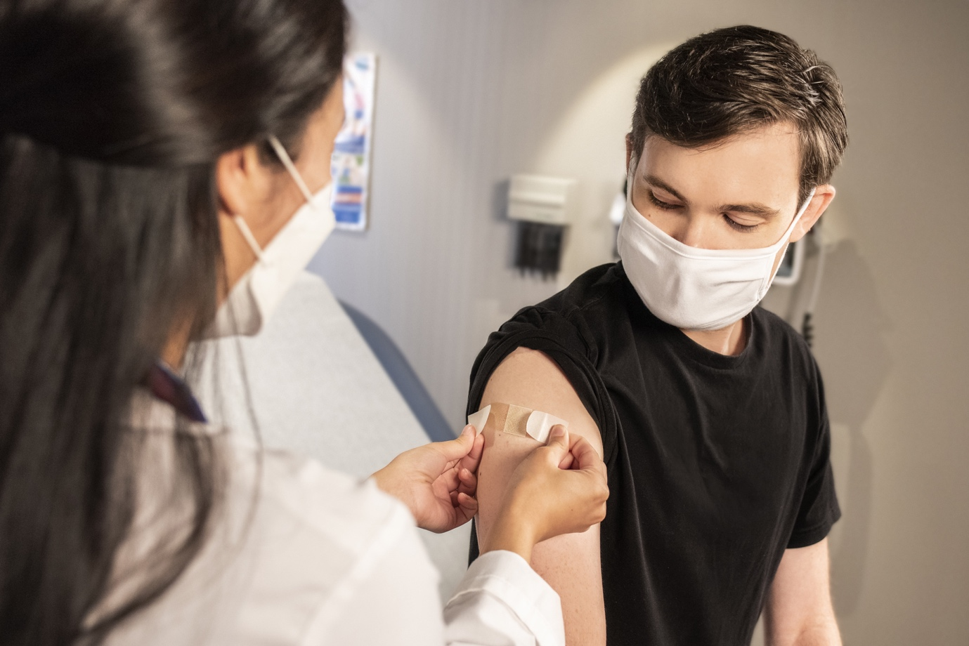 A man getting a band-aid after a shot by a nurse