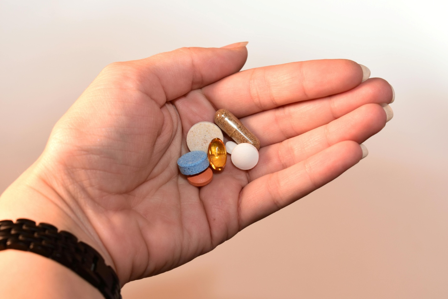 A cropped person's hand holding pills and capsules