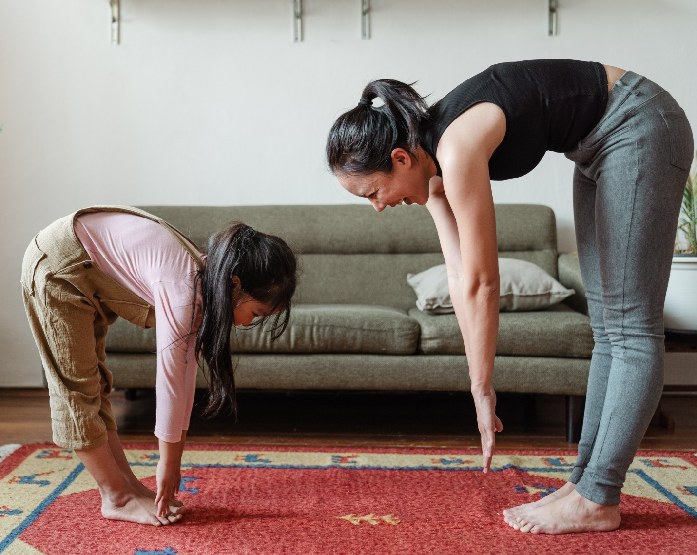 A mother teaching her daughter how to touch her toes when exercising