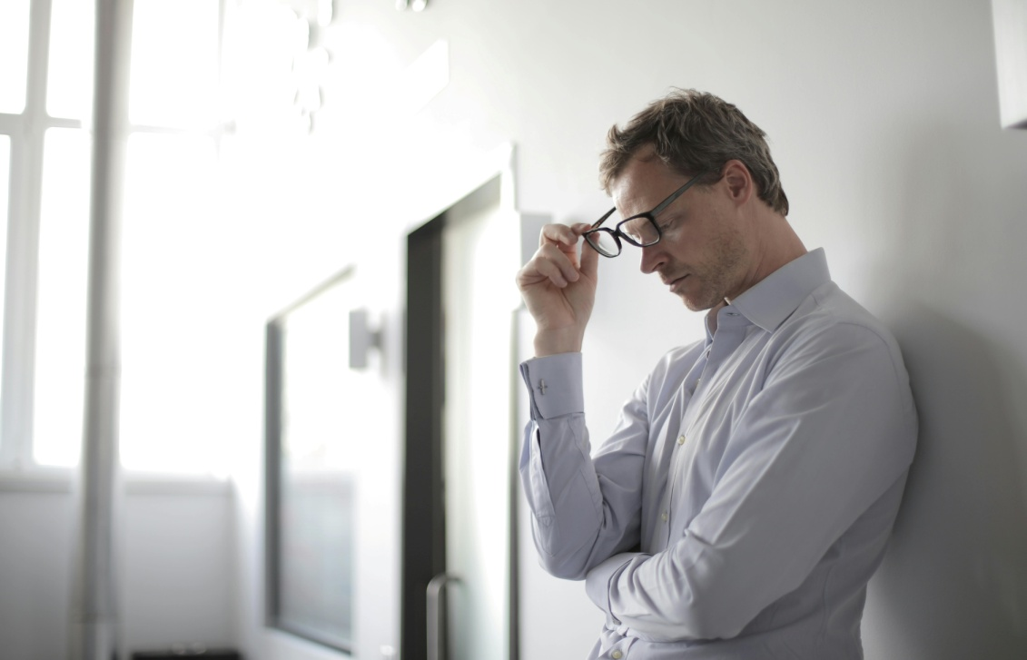  A man holding his glasses and looking tense.