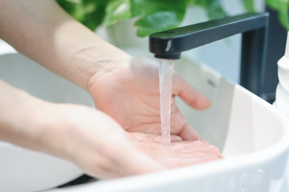 person washing hands using tap water