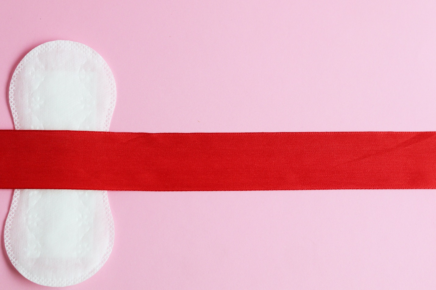 A sanitary napkin lying open on a pink surface