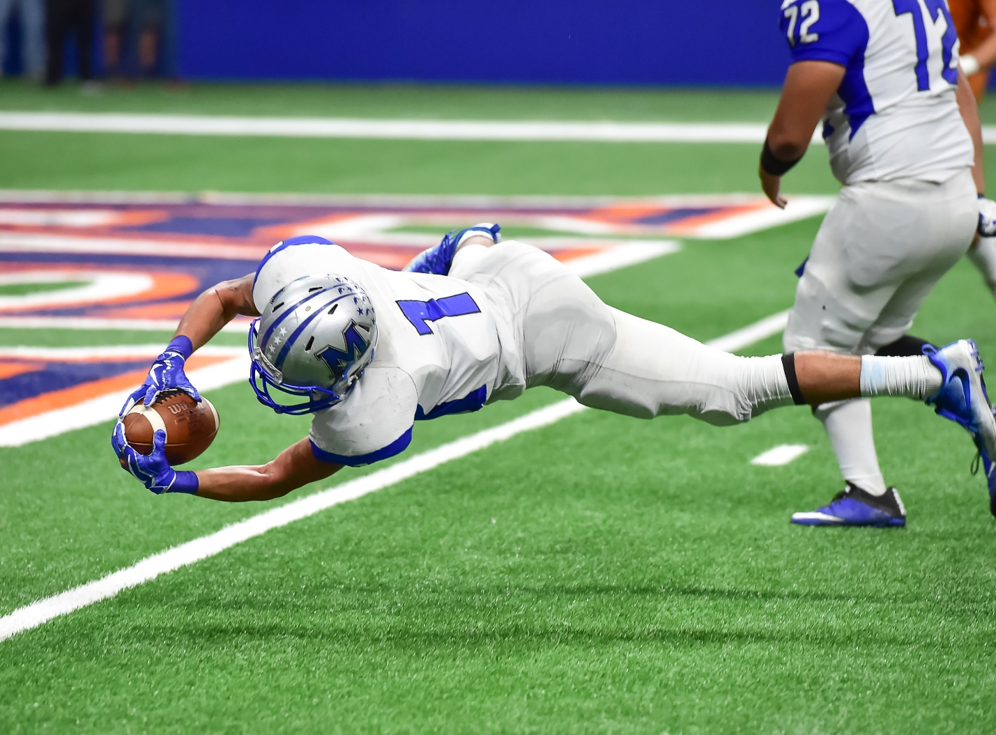 A player falls to the ground with football in his hand