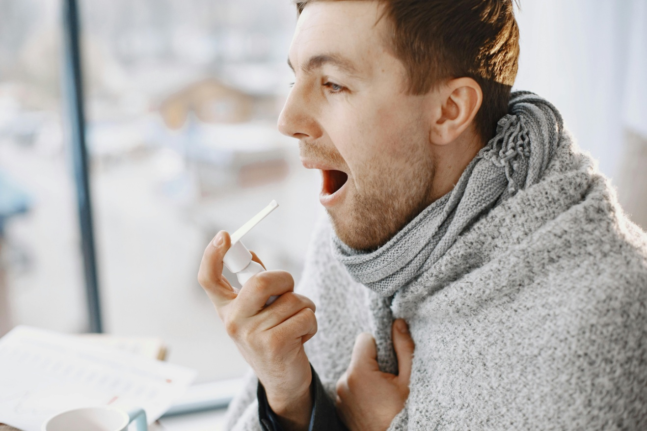 A man taking medication for his throat.