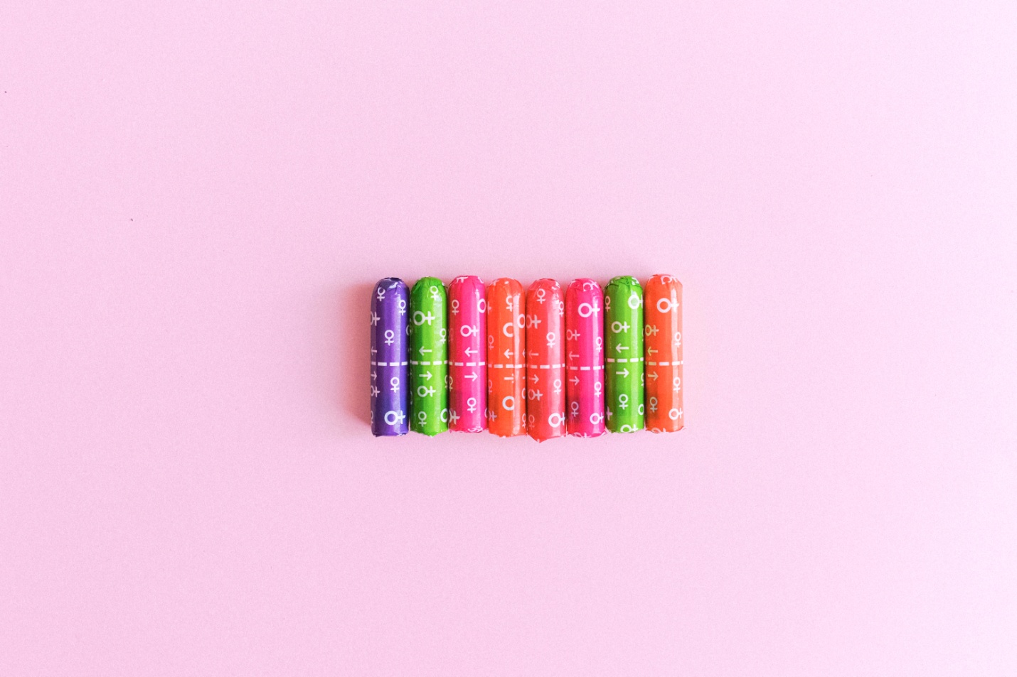 Eight tampons in a vibrant packaging lying in a row