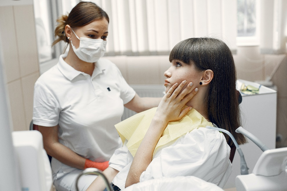 A woman with her hand on her cheek at a dentist’s office