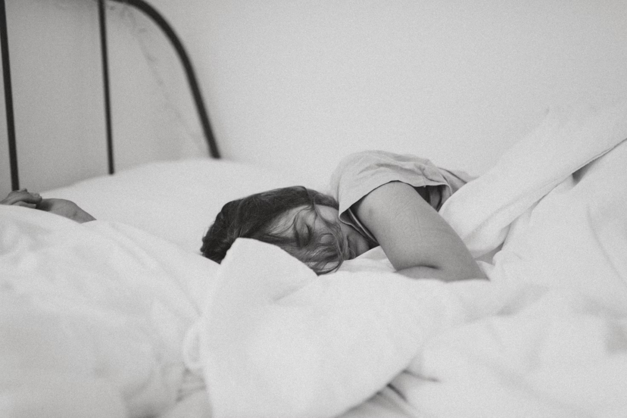 Grayscale photo of a woman sleeping in a bed