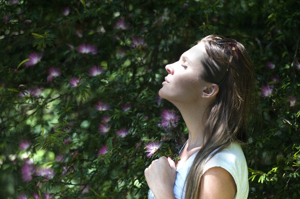 Woman standing near a bush with her eyes closed