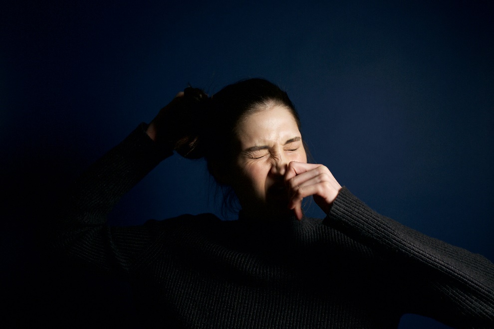 a woman wearing black sneezing