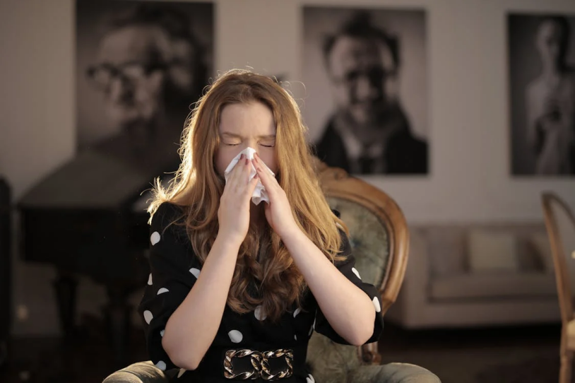 A woman sneezing due to seasonal allergies.