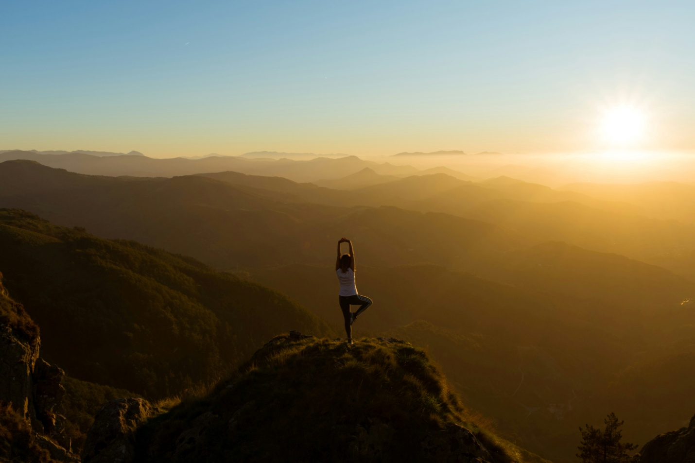 Woman stretching on a mountain top during sunrise