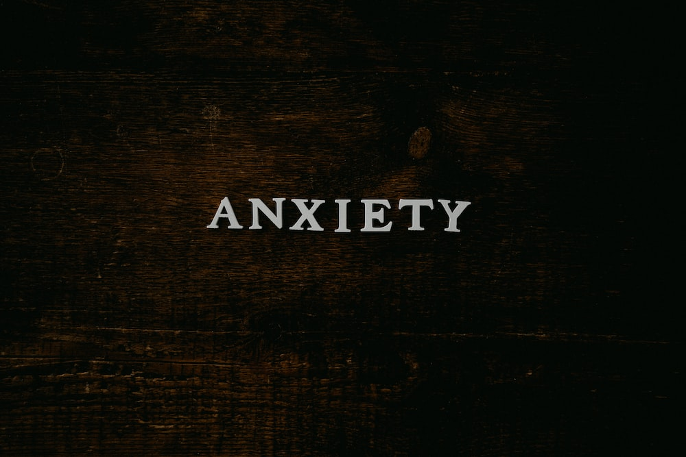 Image Alt-Text: The word “anxiety” on a brown background
