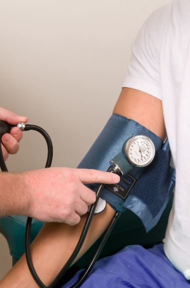 A person checking another person's blood pressure with a manual measurement tool