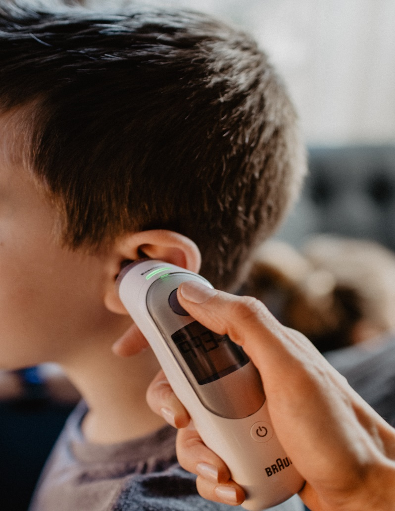 An ear thermometer is being used to check the fever of a boy