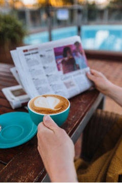 a person holding a cup of coffee and a newspaper