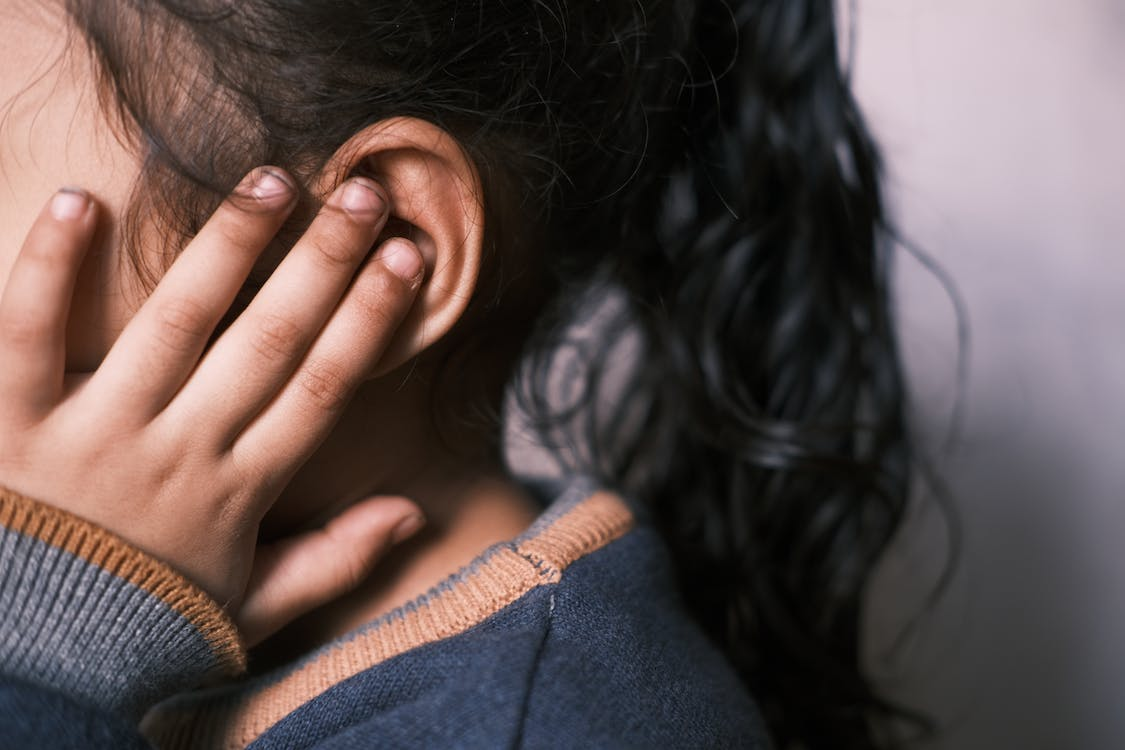 A close-up of a girl with her hand on her ear