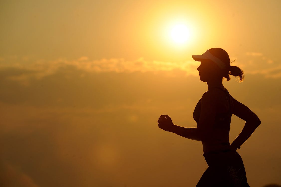 A woman is jogging with the sun rising in the background