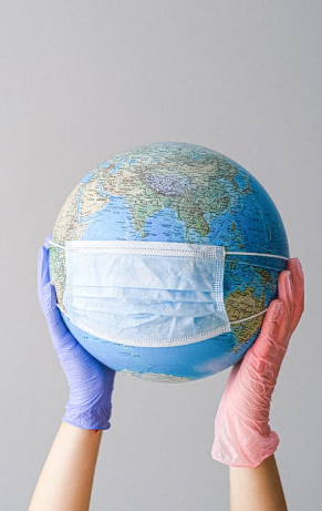 Two gloved hands holding up a globe with a mask on it
