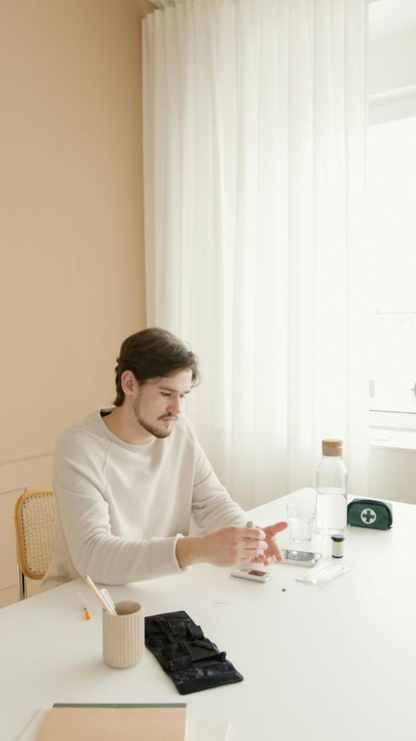 A man in a white shirt checking his blood sugar level using a glucometer