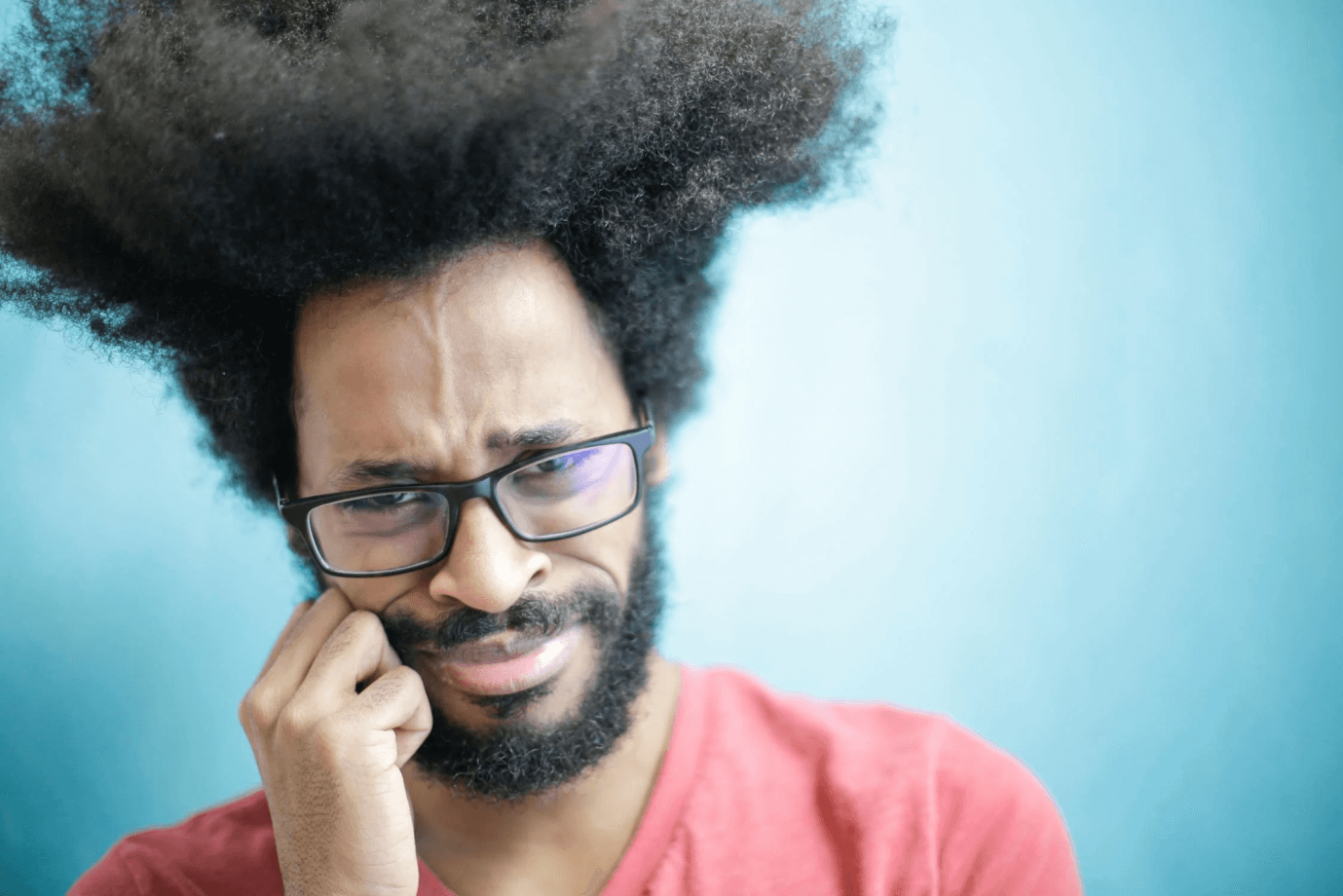 A man holding his cheek out of tooth pain.