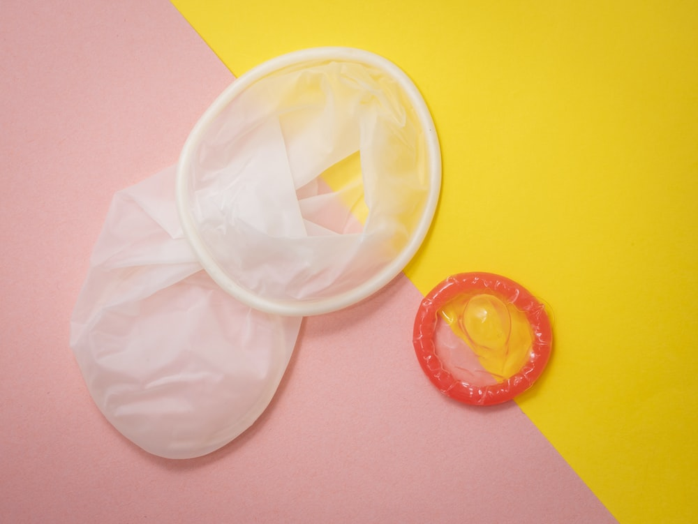 Red and white condoms on a pink and yellow background