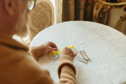 A man is refilling prescriptions on time in a pill organizer 