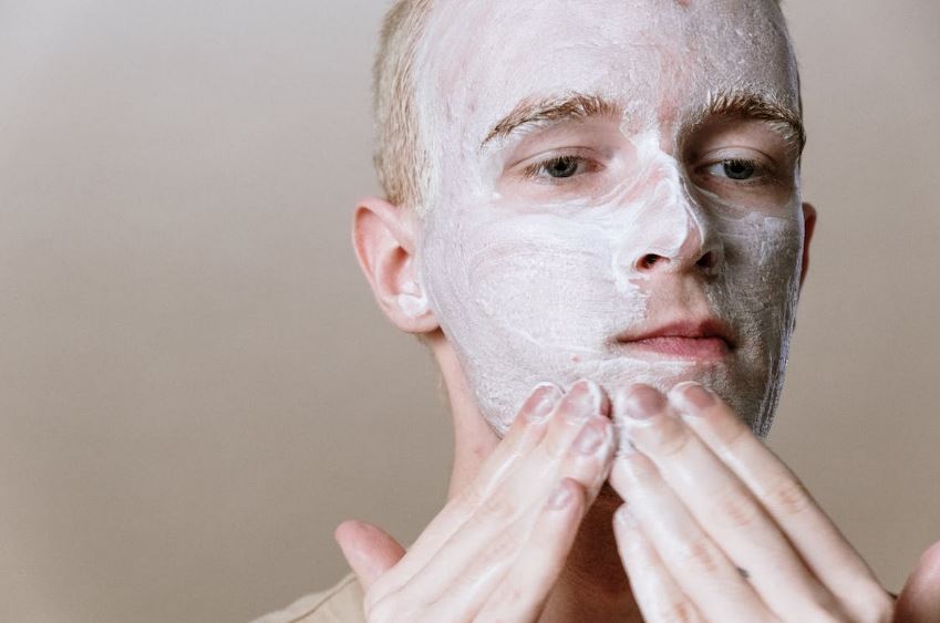 a man putting acne cream on his face 