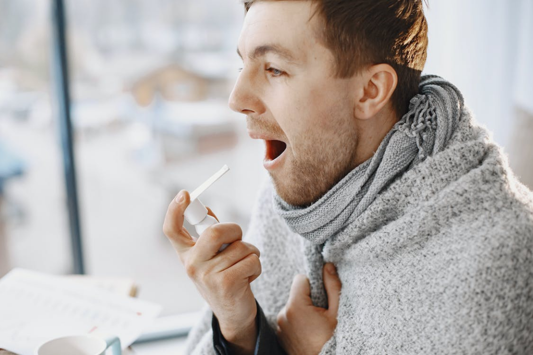 A photo of a man taking medicine for his throat