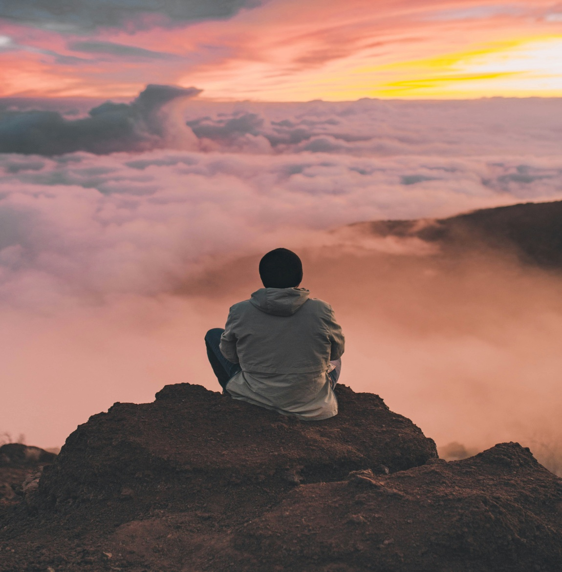 Man sitting on a cliff watching the sunset 