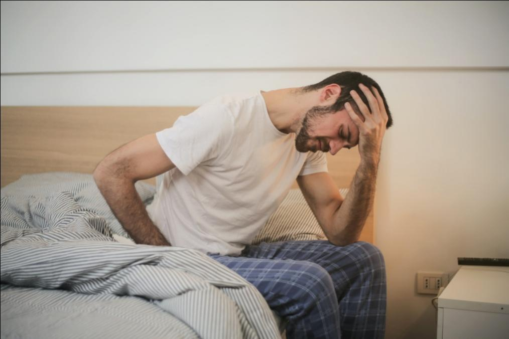 Man sitting on the bed holding his head