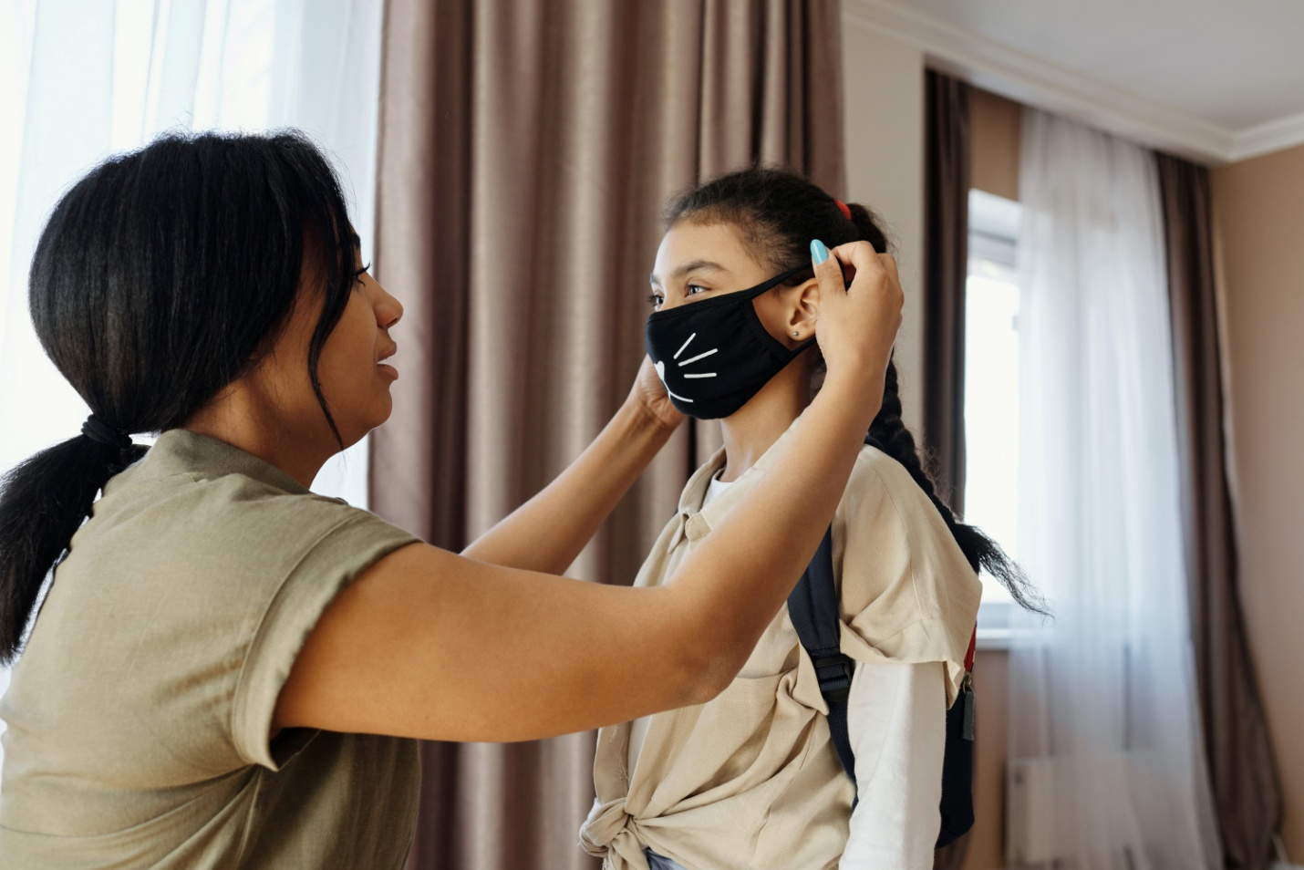 A mother putting a face mask on her daughter