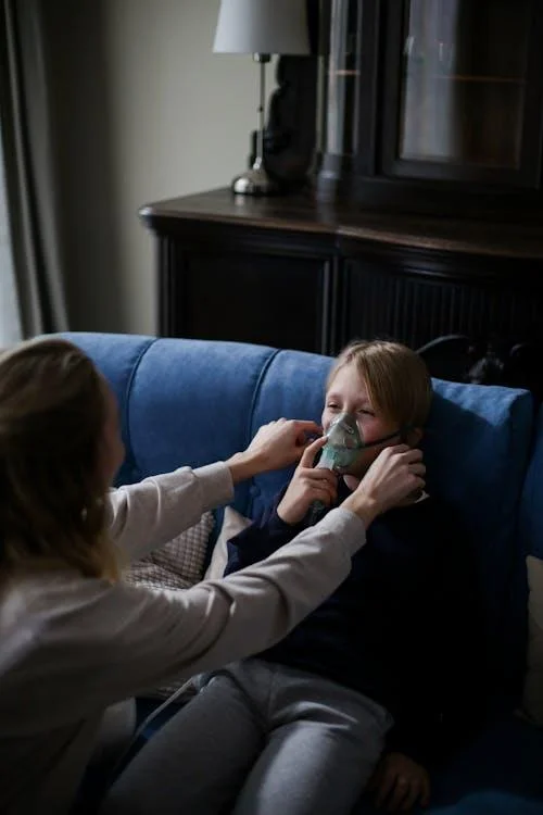 Young boy using an inhaler with his mother's help