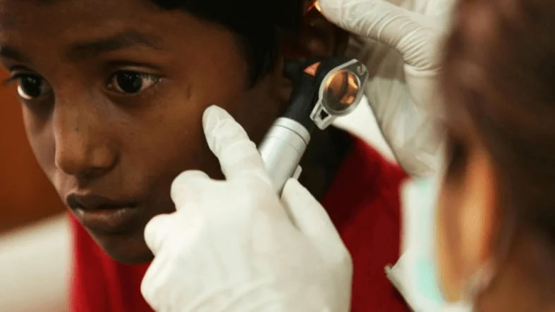 A young boy having his ear examined with an otoscope by a healthcare professional.