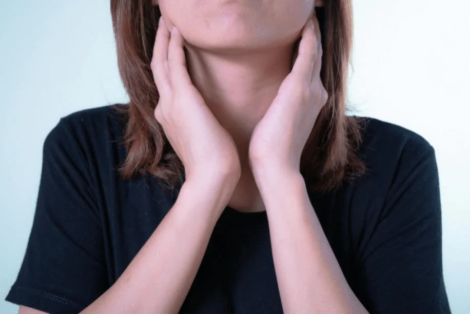 A girl massaging her throat, visibly uncomfortable and experiencing pain.