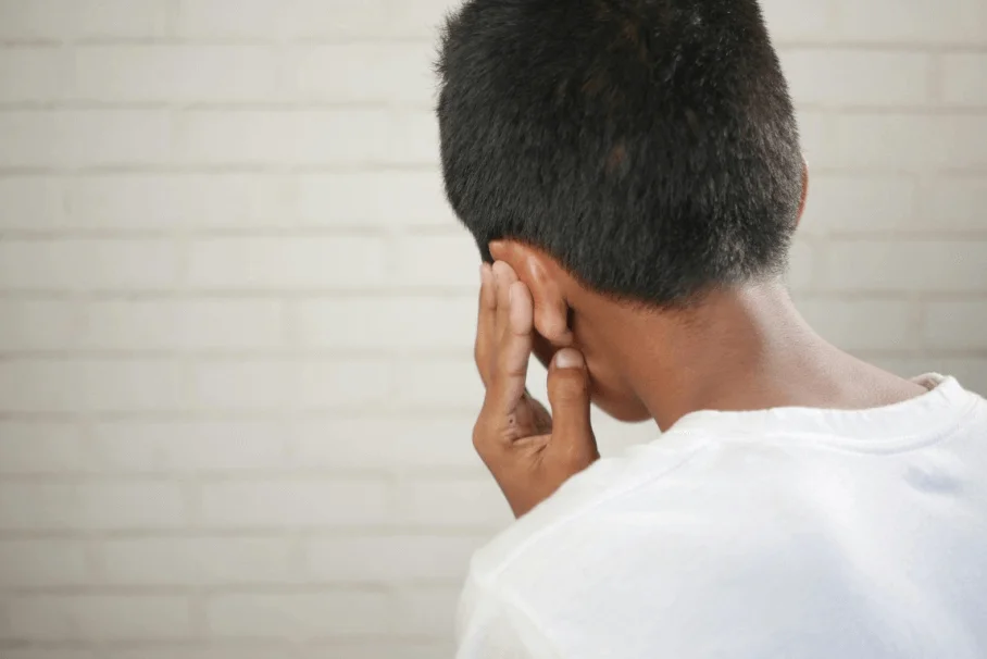 Young boy holding his ear indicating pain