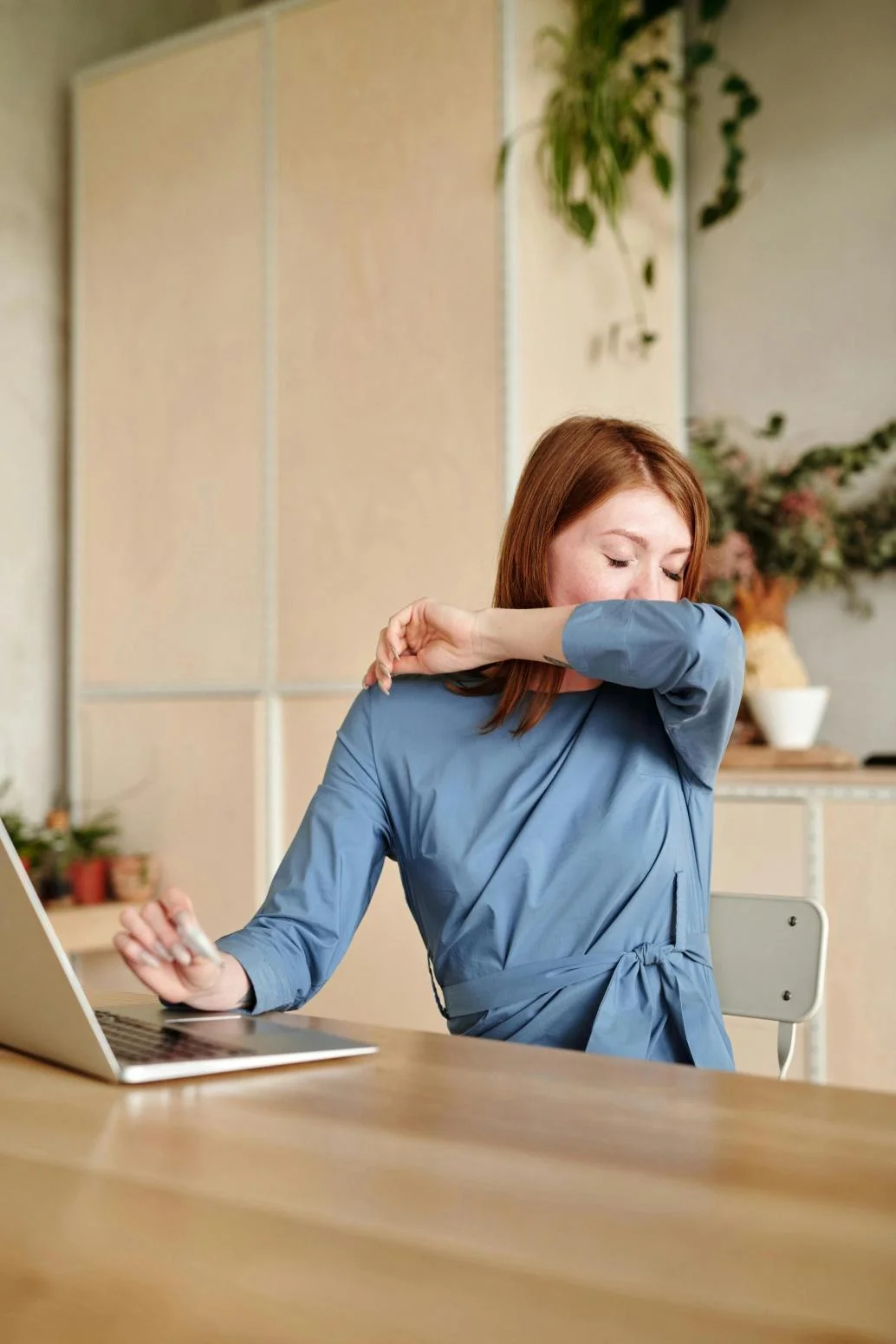 A girl sneezing or coughing, while using a laptop