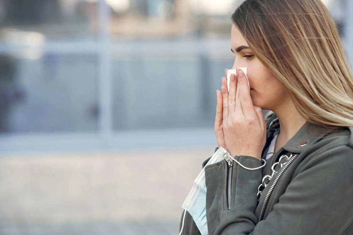 A girl sneezing and using a tissue