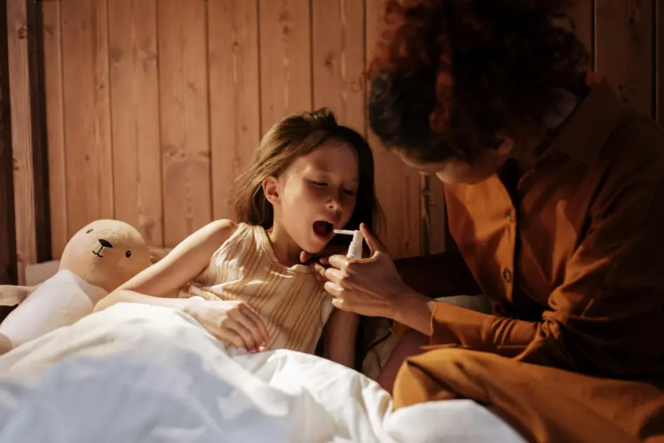 A mother giving her daughter medical treatment for flu before bedtime