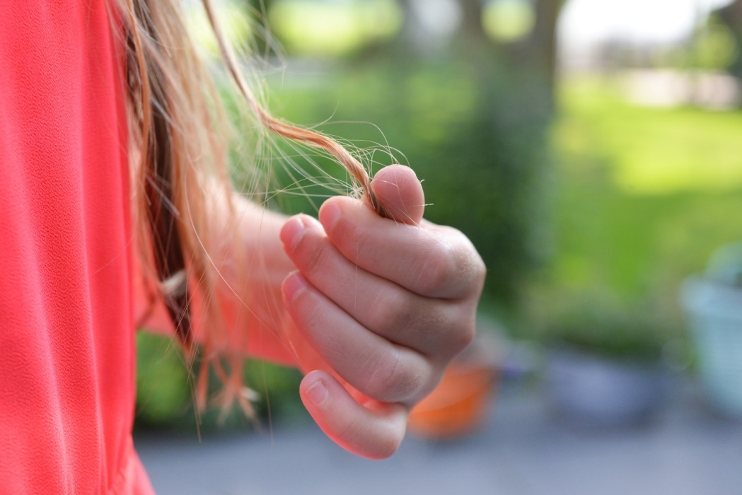 A person holding a strand of their hair  