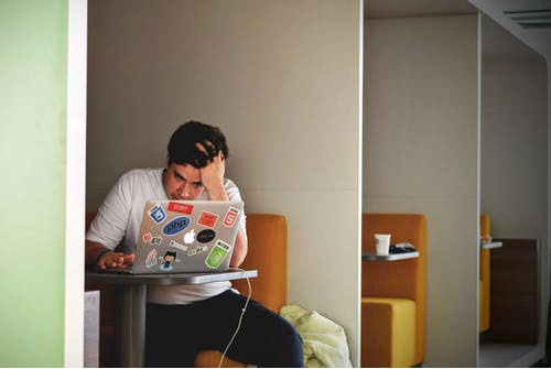 a stressed out person holding his head while working on a laptop