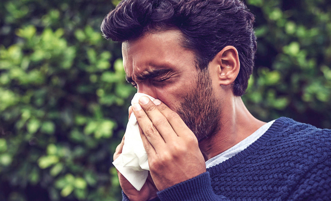 A person with winter allergies wiping his nose
