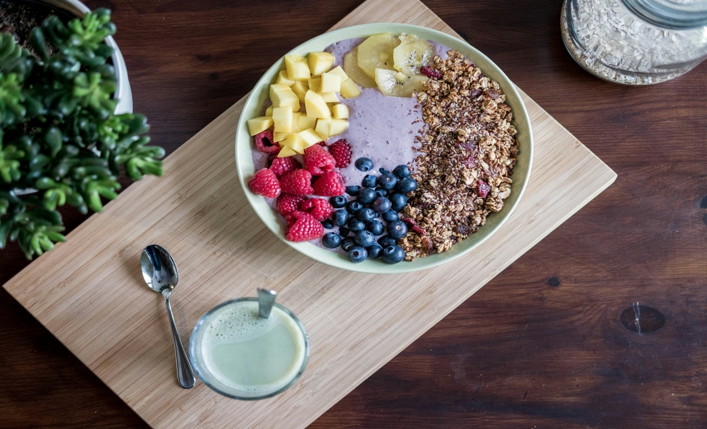 A fruit bowl with yogurt along with a spoon 